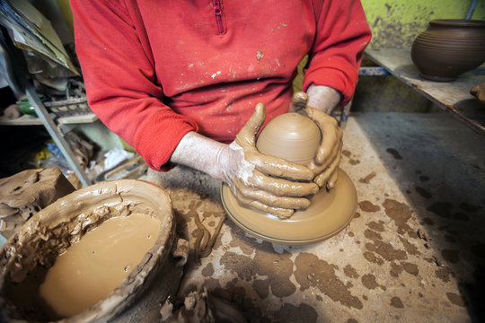 Creating a jar or vase of white clay close-up. Master crock. Man hands making clay jug macro. The sculptor in the workshop makes a jug out of earthenware closeup. Twisted potter's wheel.