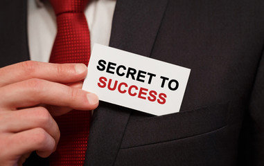 Businessman putting a card with text Secret to Success in the pocket