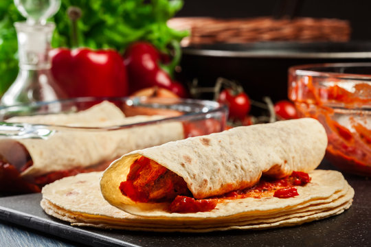 Preparation traditional mexican enchiladas with chicken meat, spicy tomato sauce and cheese