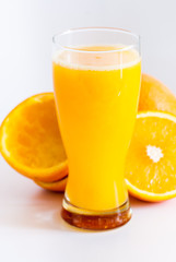 glass with fresh squeezed orange juice and oranges on white healthy life concept