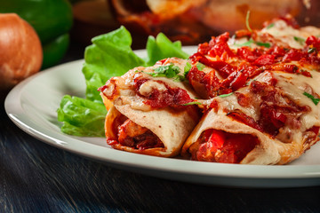 Traditional mexican enchiladas with chicken meat, spicy tomato sauce and cheese on a plate