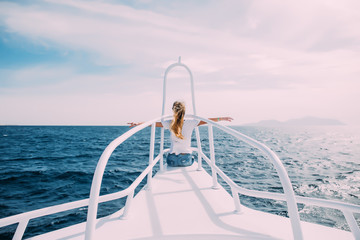 Young girl on the nose of the white yacht with raised hands to the wind the open sea or ocean