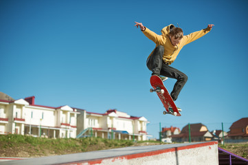 A teenager skateboarder does an ollie trick in a skatepark on the outskirts of the city