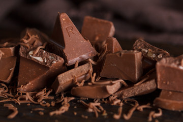 Milk chocolate. Milk chocolate pieces on a wooden background