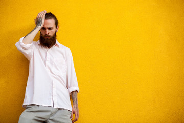 Cool bearded hipster on yellow wall posing outdoor