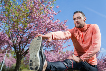Fototapeta na wymiar Sportler dehnt sein Bein nach dem Laufen und Training