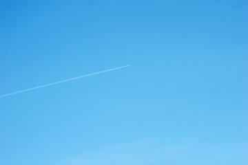 The airplane is flying under the blue sky