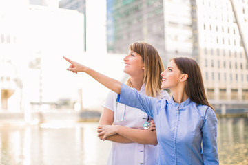 Two young medical workers stand together and look aside outdoor