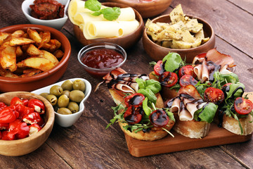 Italian antipasti wine snacks set. Cheese variety, Mediterranean olives, pickles, Prosciutto di Parma, tomatoes, artichokes and wine in glasses