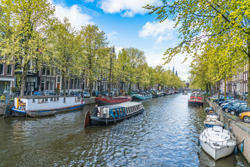 Naklejka premium Amsterdam, The Netherlands, April 22, 2017: Local and tourist walking on the Keizersgracht Canal in spring in the Jordaan area with boats, bikes and cars