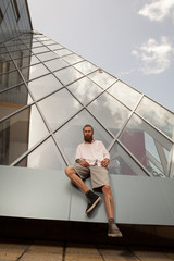 Cool bearded tattooed hipster posing in front of office building. Modern start up company