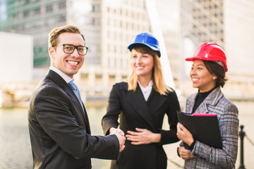 Happy smiling businessman concluded contract about new project with architects and they shake hands, outdoors