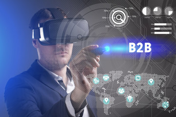 Business, Technology, Internet and network concept. Young businessman working in virtual reality glasses sees the inscription: B2B