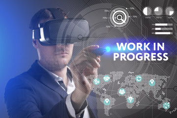 Business, Technology, Internet and network concept. Young businessman working in virtual reality glasses sees the inscription: Work in progress