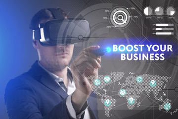 Business, Technology, Internet and network concept. Young businessman working in virtual reality glasses sees the inscription: Boost your business