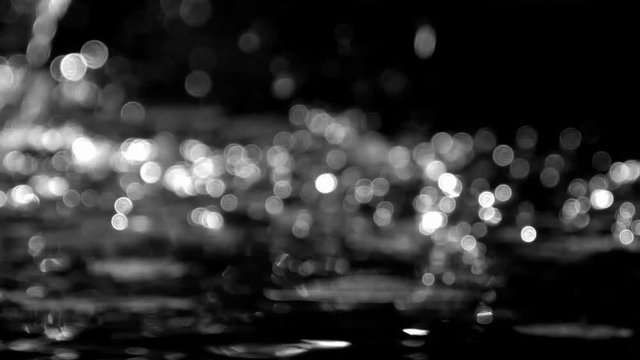 Fast moving bokeh from water drops in the sun in black and white.