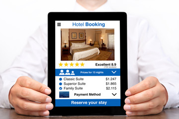 man hands holding tablet computer with app hotel booking screen