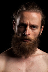Obraz premium Tattooed bearded hipster on black background in studio photo. Expression and fashion
