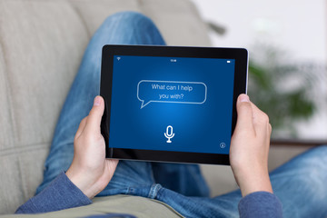 man on sofa holding tablet with app personal assistant screen