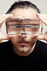 Reflection of a male face in glasses with liquid 