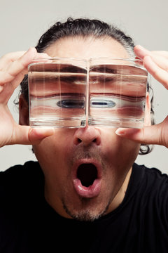 Reflection of a male face in glasses with liquid 