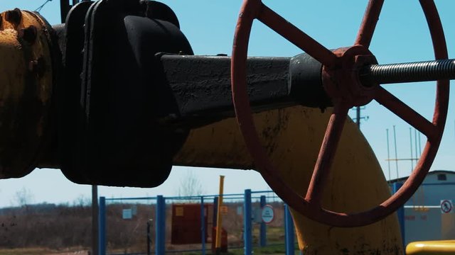 Valve on oil and gas pipeline. A processing and storage station for natural gas. oil industry. Close-up of the shut-off valve against the background of the reprocessing station.