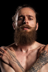 Cool bearded hipster on black background in studio photo. Expression and fashion