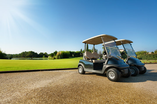 Two golf-carts standing at the parking in summer