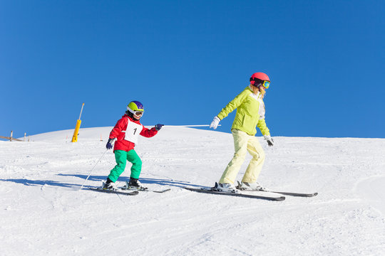 Sporty mother pulling her kid son on ski by a pole
