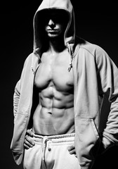 Fototapeta na wymiar Portrait of strong healthy handsome Athletic Man Fitness Model posing near dark gray wall