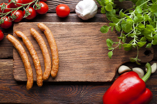 Sausage, vegetables and herbs on wooden board