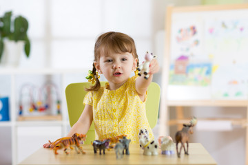 Child playing with animal toys at table
