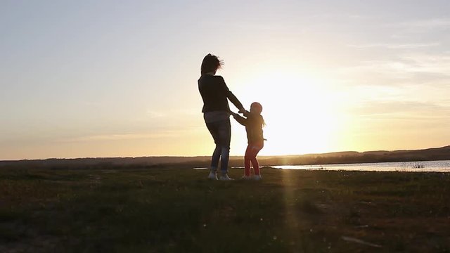 Silhouette, happy child with mother and father, family at sunset, summertime. Run, raising baby up in the air, hugs, love, playing. We are happy family.