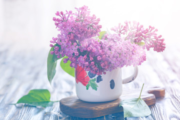 Bouquet of lilacs in an old enamel mug, toning.
