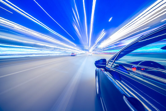 View From Side Of Car Moving In A Night City, Blured Road With Lights With Car On High Speed. Concept Rapid Rhythm Of A Modern City.