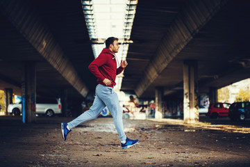 Man in red hoodie running under overpass