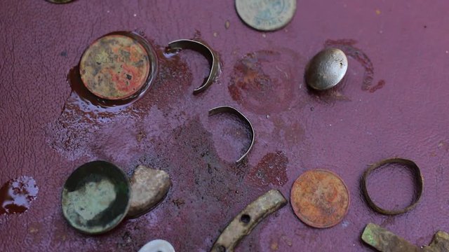 Closeup of different old things that were find deep in soil with help of metal detector. Dirty and rusty coins, rings, buttons, crosses and other.  Real time full hd video footage.