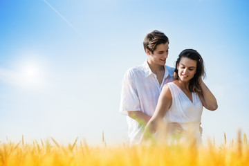 Obraz premium Happy, young couple enjoying in the wheat field, summer season. Sunset light, flare light, copy space 