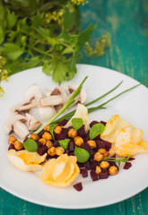 Vegetarian salad of beets, roasted peas, greens, corn chips and fresh champignons. Wooden turquoise background. Close-up