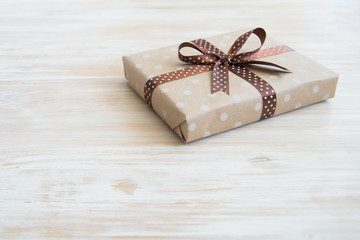 Box in craft paper, eco paper on the wooden table. Top view. Brown paper wrapped gift box with satin ribbon bow on a old rustic wood background. Background for your design. Retro filter
