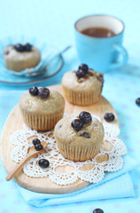 Blueberry Muffins on wooden board, on light blue background.