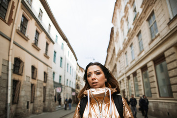 Fototapeta premium Girl in golden suit stands on the old European street