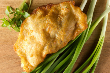 Fried cheburek with meat with green onions and Basil on wooden background