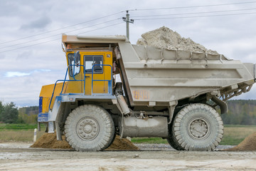 Large-yellow quarry dump trucks produce transportation of minerals