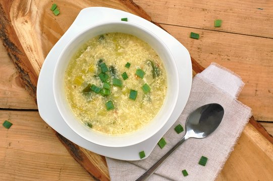 gluten free soup from leek, egg, polenta and parmesan on wooden background
