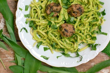 Food with pasta, green pesto,meatballs on white plate on wooden background