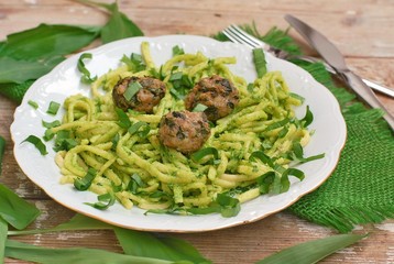 Food with pasta, green pesto,meatballs and buckrams on white plate on wooden background