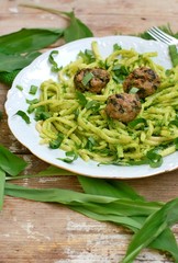 Food with pasta, green pesto,meatballs and buckrams on white plate on wooden background