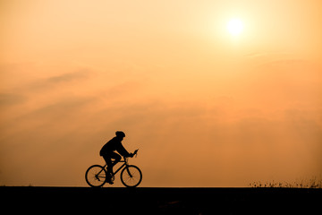 Fototapeta na wymiar Silhouette of cyclist on sunset background