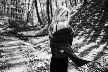 Woman envelopes herself in the coat posing in the forest